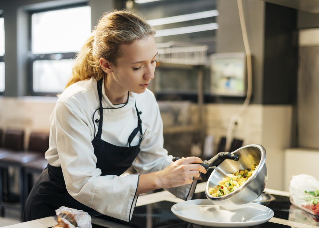 Female chef pouring food on plate